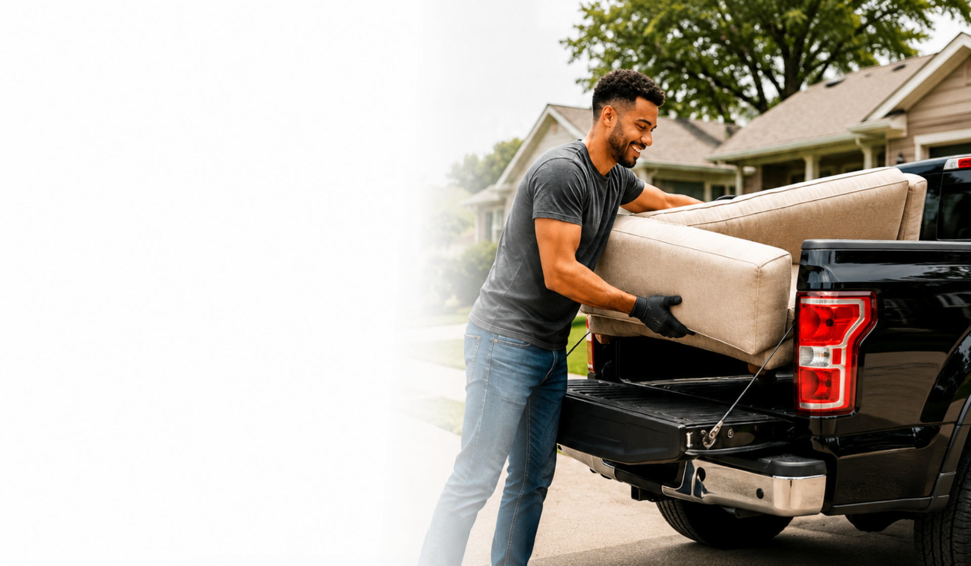 Local driver loading a sofa into a pickup truck in a suburban neighborhood